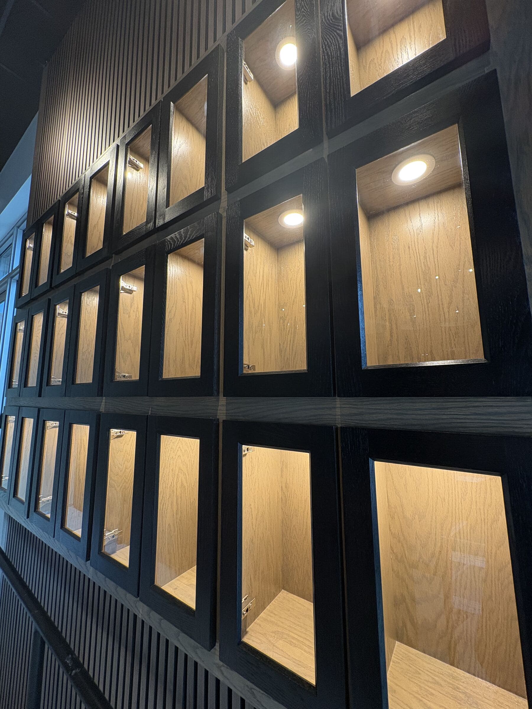 Close view of the lit oak interiors and black frames of the tequila lockers